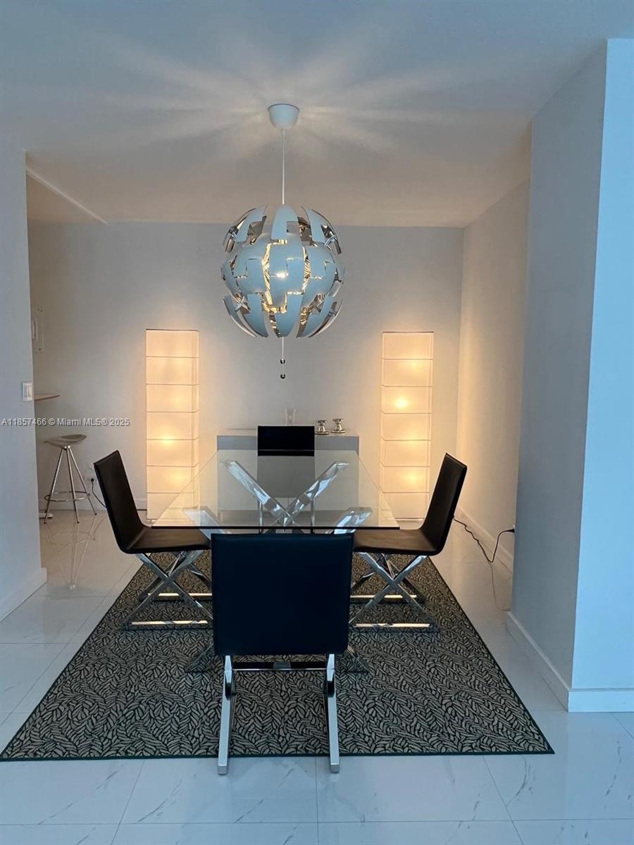 A dining room features a glass table, black chairs, a spherical pendant light, and floor lamps — 5601 Collins Ave # 1115, Miami Beach FL 33140, MIAMI BEACH, FL