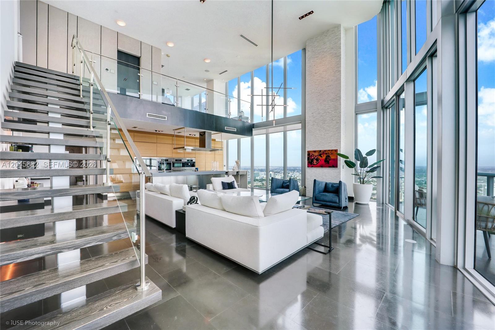 A modern two-story living room features floor-to-ceiling windows, a floating staircase, and white sofas — 888 Biscayne Blvd # 5112, Miami FL 33132, MIAMI, FL