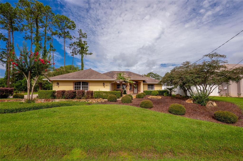 A single-story house with a tan exterior, a brown roof, and a landscaped front yard — 30 EVANS DRIVE, PALM COAST, FL