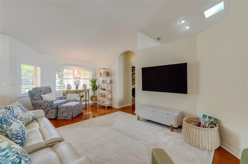 A living room features a wall-mounted television, a white sofa, and a patterned armchair — 30 EVANS DRIVE, PALM COAST, FL