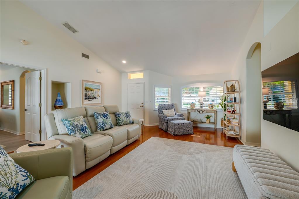 A living room features light-colored leather furniture, a patterned area rug, and hardwood flooring — 30 EVANS DRIVE, PALM COAST, FL