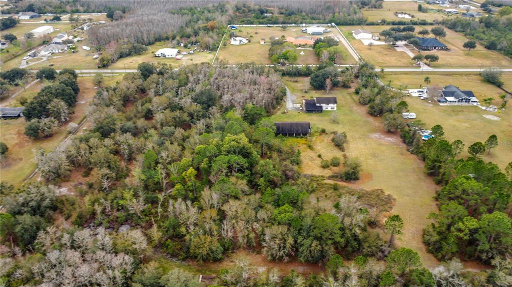 An aerial view shows a rural property with wooded areas, open fields, and several houses — TWILIGHT TRAIL, KISSIMMEE, FL