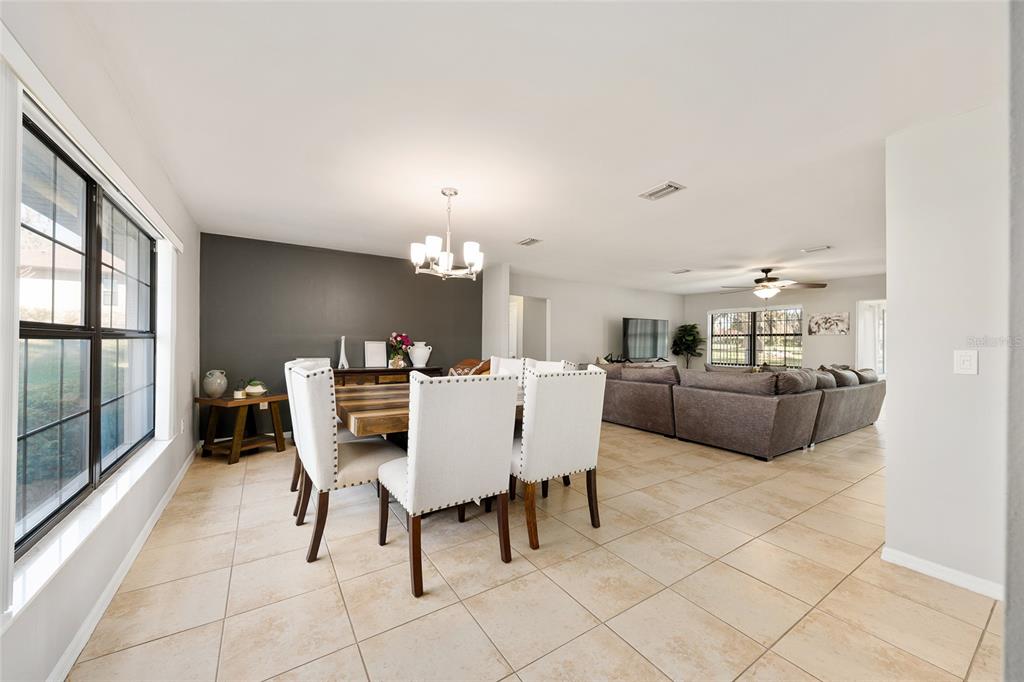 A dining area with white chairs and a dark accent wall opens into a living room — 5201 NW 78TH COURT, OCALA, FL