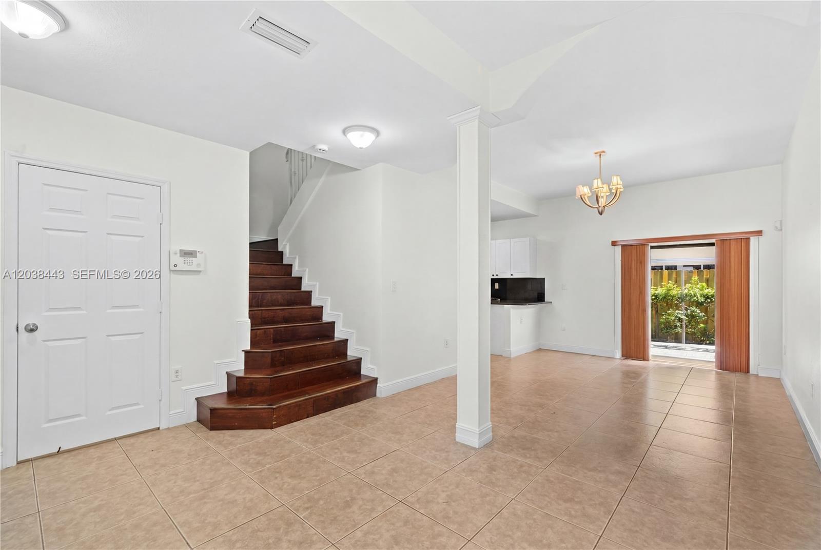 An open-concept room features tile flooring, a wooden staircase, and a sliding glass door — 7362 NW 179th Ter # 7362, Hialeah FL 33015, HIALEAH, FL