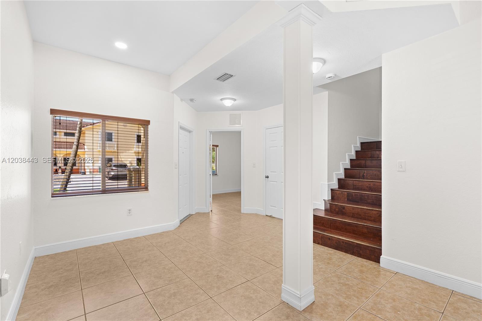 An interior view shows a tiled room with a wooden staircase and white walls — 7362 NW 179th Ter # 7362, Hialeah FL 33015, HIALEAH, FL