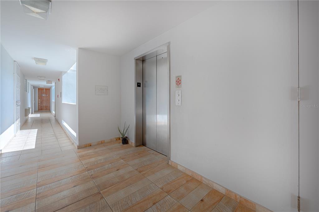 An elevator with a number four sign sits in a hallway with tiled floors — SR 102 km 14.6 BARRIO JOYUDA COND TORRE PUESTA DEL SOL UNIT 406, CABO ROJO, PR