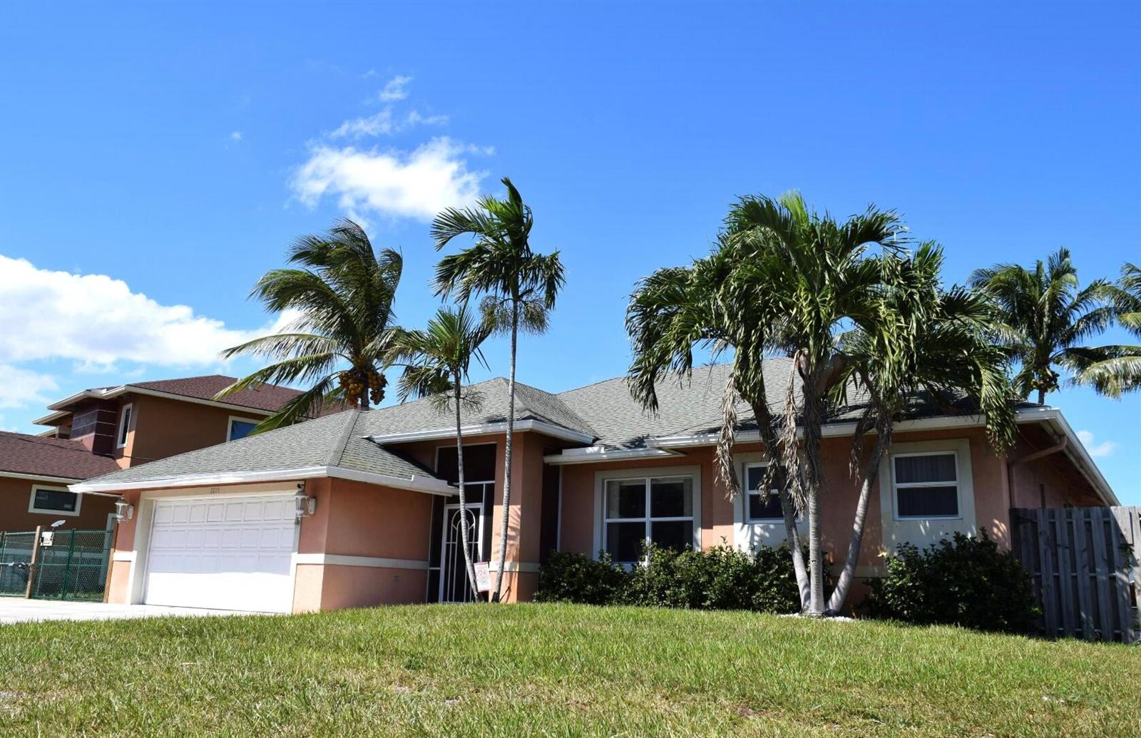 A single-story peach-colored house with a white garage door and several palm trees — 2215 Hypoluxo Rd Road, Lantana FL 33462, LANTANA, FL