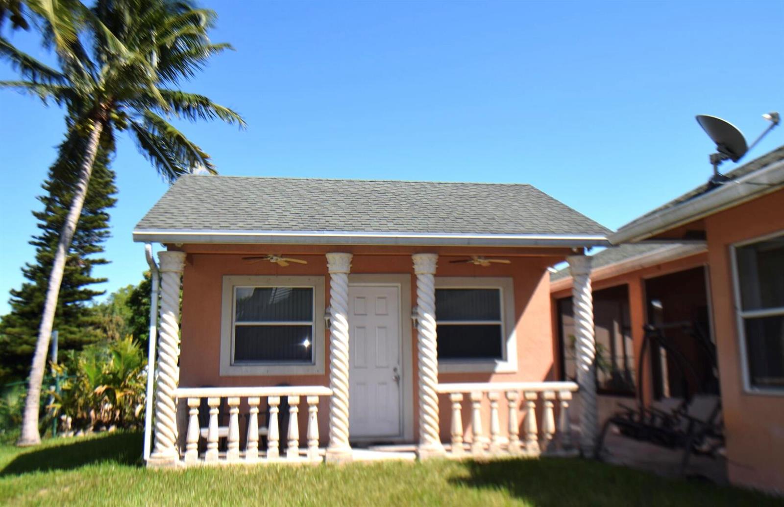 A small, peach-colored house features a front porch with white balustrades and spiral columns — 2215 Hypoluxo Rd Road, Lantana FL 33462, LANTANA, FL