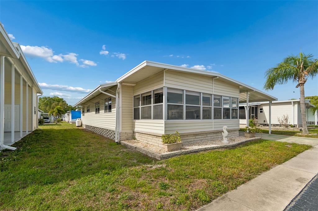 A light-colored mobile home with a screened-in porch and a palm tree in the yard — 12651 SEMINOLE BOULEVARD UNIT 15I, LARGO, FL