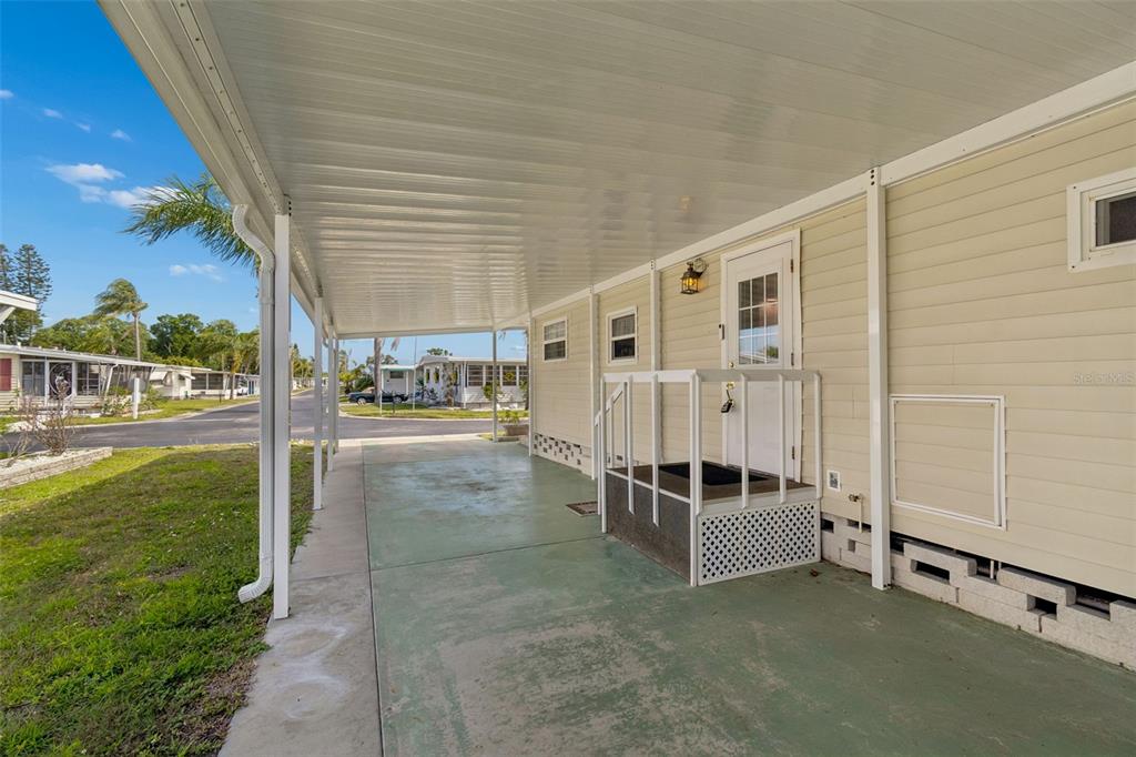 A covered concrete carport sits beside the side entrance of a light-colored mobile home — 12651 SEMINOLE BOULEVARD UNIT 15I, LARGO, FL