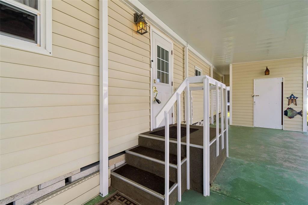 A beige mobile home exterior features a covered porch, white stairs, and a white door — 12651 SEMINOLE BOULEVARD UNIT 15I, LARGO, FL