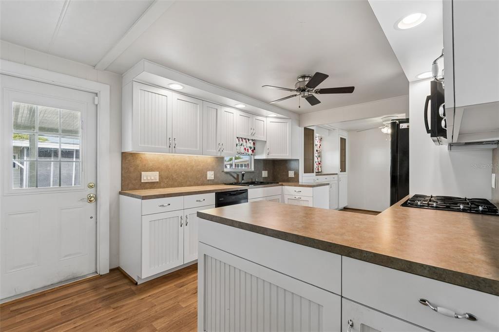 A kitchen features white beadboard cabinetry, brown countertops, a ceiling fan, and a side door — 12651 SEMINOLE BOULEVARD UNIT 15I, LARGO, FL