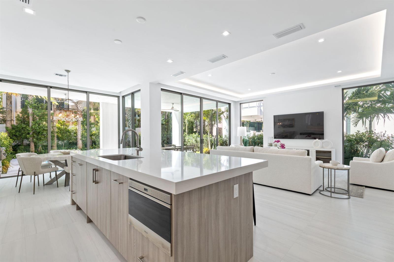A modern open-concept kitchen and living area with light wood cabinetry and floor-to-ceiling windows — 406 Ocean One Lane, Juno Beach FL 33408, JUNO BEACH, FL