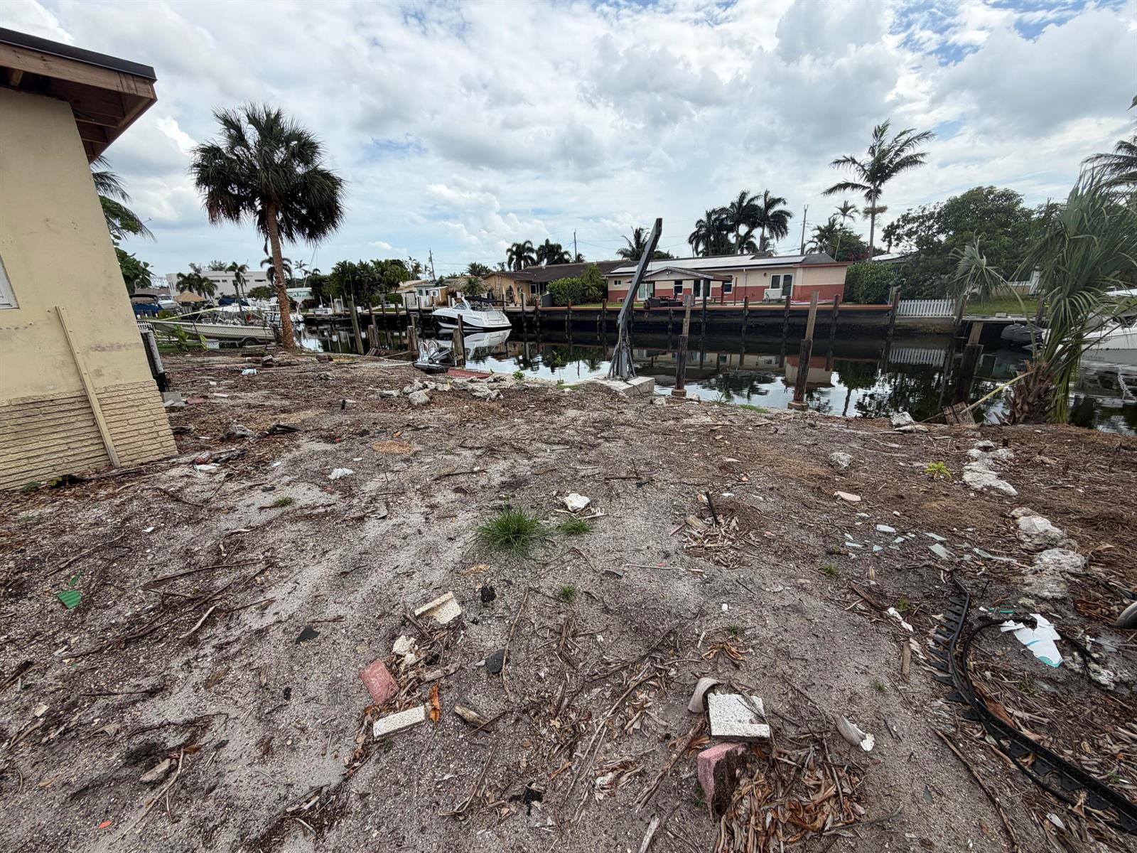 A dirt-covered waterfront lot features a boat lift, palm trees, and a canal view — 835 NW 13th Avenue, Dania Beach FL 33004, DANIA BEACH, FL