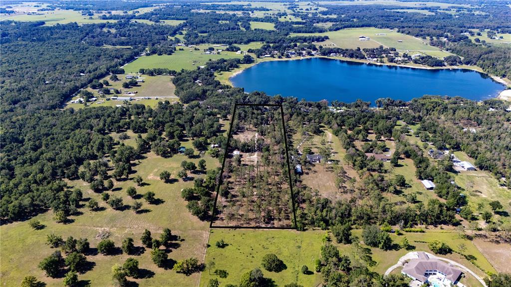 An aerial view shows a trapezoidal plot of land outlined in black amidst rural terrain — 0 REED ROAD, DADE CITY, FL