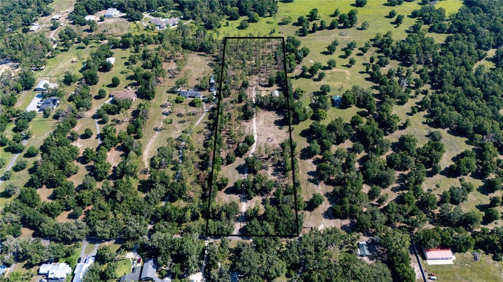 An aerial view shows a trapezoidal plot of land marked by a black boundary line — 0 REED ROAD, DADE CITY, FL