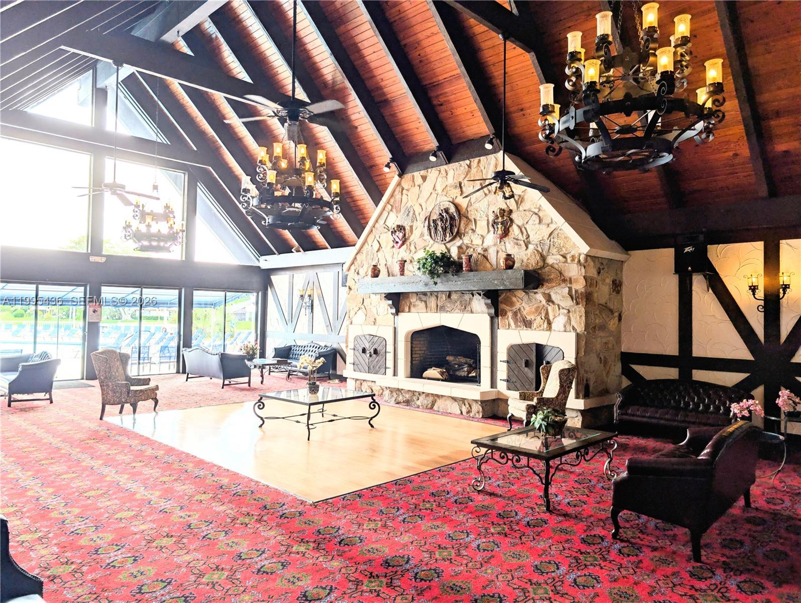 A large room features a stone fireplace, vaulted wood ceilings, chandeliers, and patterned red carpeting — 3720 Inverrary Dr # 1J, Lauderhill FL 33319, LAUDERHILL, FL