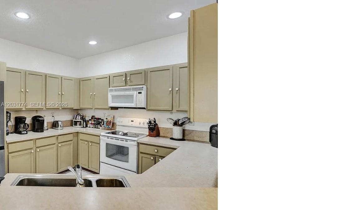 A kitchen features light green cabinets, white appliances, and light-colored countertops — HOMESTEAD, FL