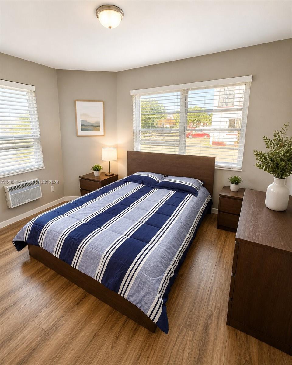 A bedroom features a bed with a striped comforter, wood-look flooring, and two windows — 375 SW 19th Ave # 2, Miami FL 33135, MIAMI, FL
