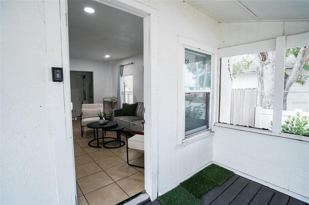 A view from a covered porch looking through an open doorway into a tiled living room — 1361 29TH STREET S, ST PETERSBURG, FL