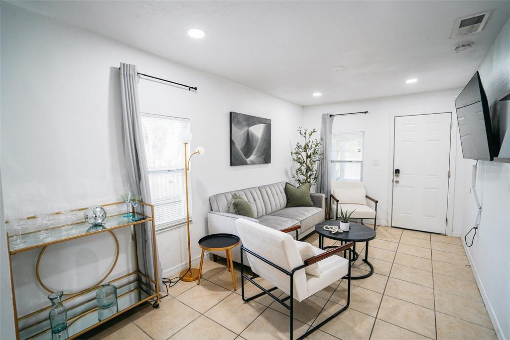 A living room features a grey sofa, white accent chairs, a bar cart, and tile flooring — 1361 29TH STREET S, ST PETERSBURG, FL