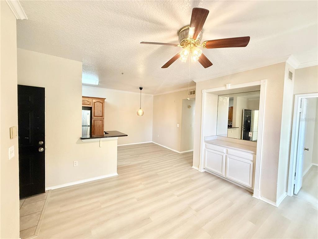 An open-concept living and dining area features light wood-look flooring, a ceiling fan, and cabinetry — 2528 ROBERT TRENT JONES DRIVE UNIT 1625, ORLANDO, FL