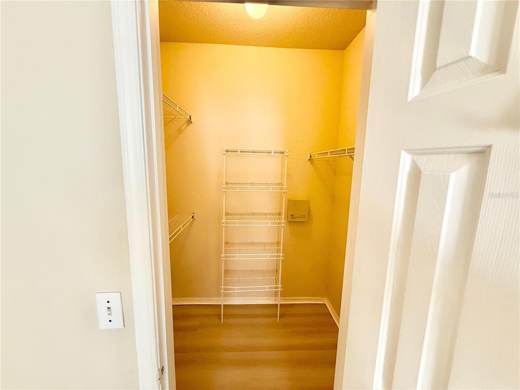 A walk-in closet features white wire shelving, light-colored walls, and wood-look flooring — 2528 ROBERT TRENT JONES DRIVE UNIT 1625, ORLANDO, FL