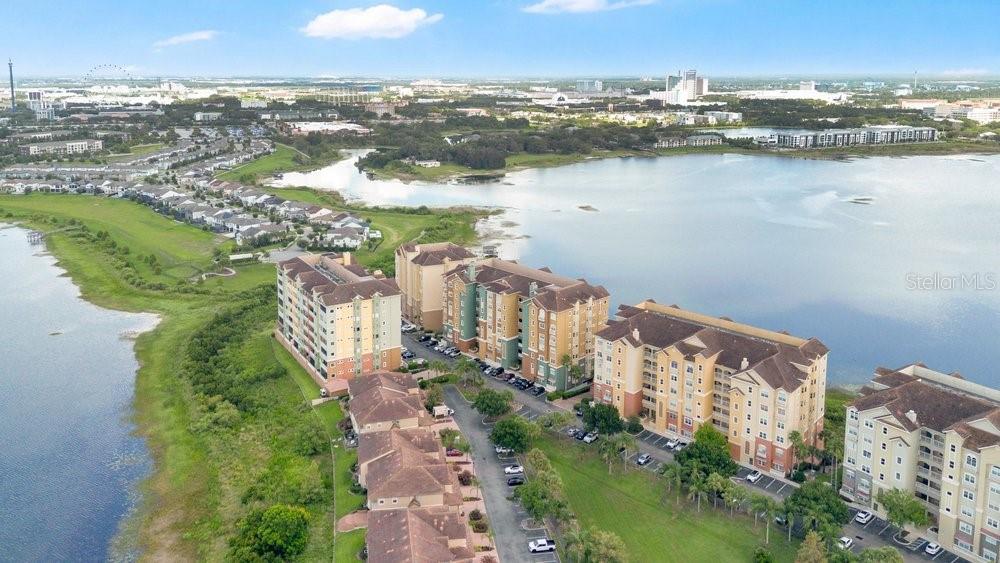 An aerial view shows multi-story apartment buildings situated along a large lake and residential neighborhood — 8749 THE ESPLANADE UNIT 22, ORLANDO, FL