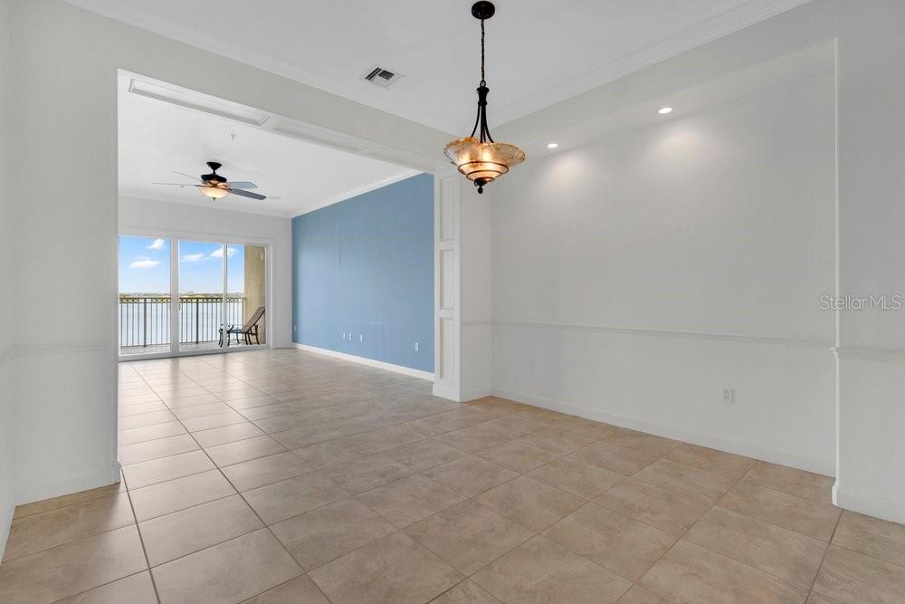 A dining area with tile floors and a chandelier leads to a living room balcony — 8749 THE ESPLANADE UNIT 22, ORLANDO, FL