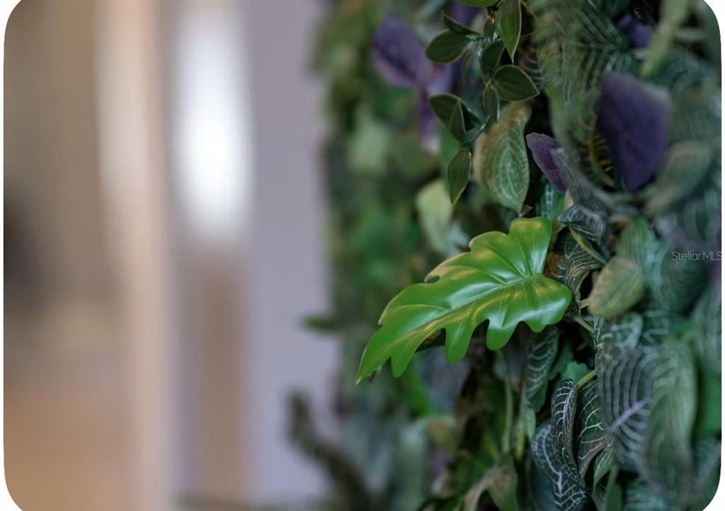 A close-up view of a decorative artificial green wall featuring various leaf shapes and textures — 9093 SOMMERSET HILLS DRIVE, DAVENPORT, FL