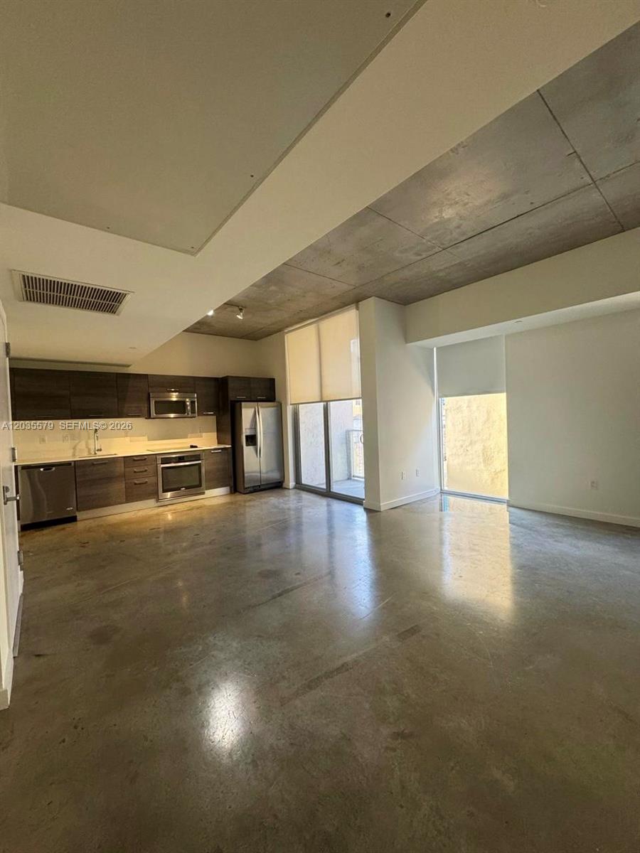 An open-concept kitchen and living area features concrete ceilings, polished concrete floors, and stainless appliances — 151 SE 1st St # 408, Miami FL 33131, MIAMI, FL