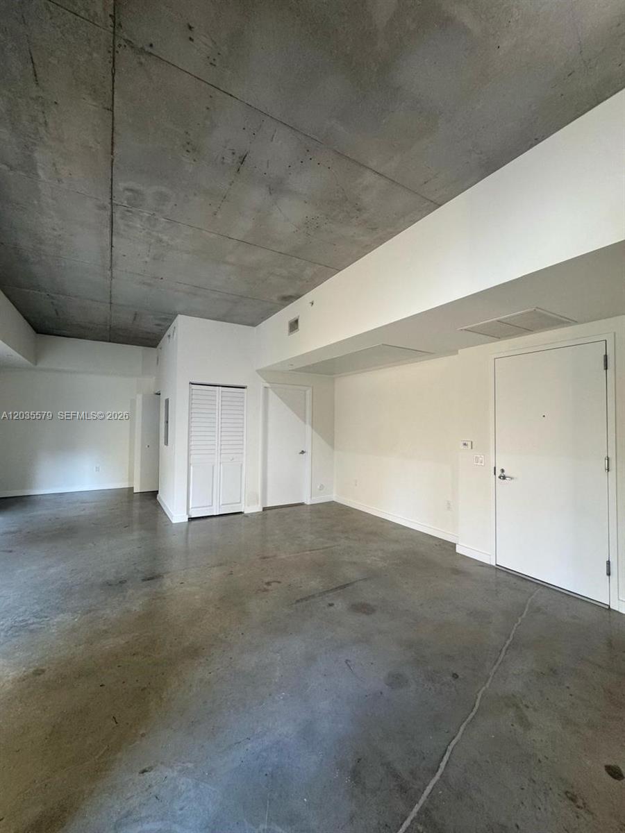 An empty room features a concrete ceiling, polished concrete floors, and white interior doors — 151 SE 1st St # 408, Miami FL 33131, MIAMI, FL