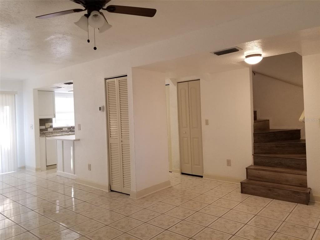 A tiled living area features a ceiling fan, two closet doors, and wooden stairs — 5134 TENNIS COURT CIRCLE, TAMPA, FL