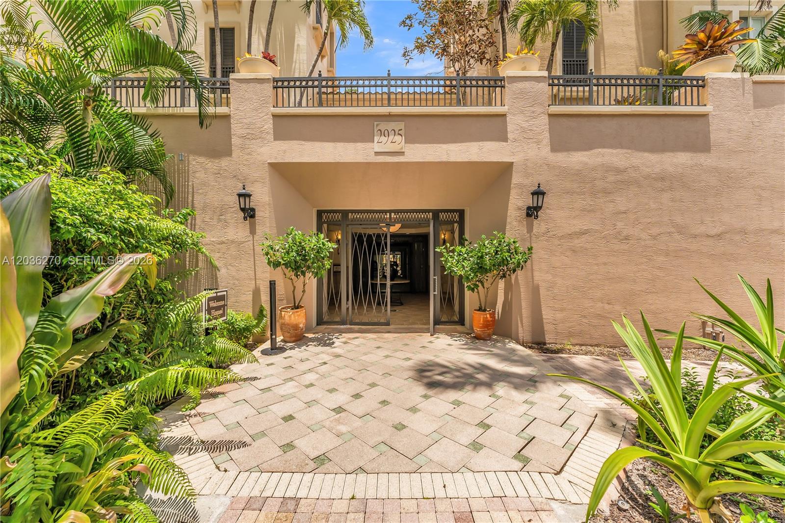 An exterior view of a building entrance with a paved walkway and potted plants — 2925 NW 126th Ave # 1, Sunrise FL 33323, SUNRISE, FL
