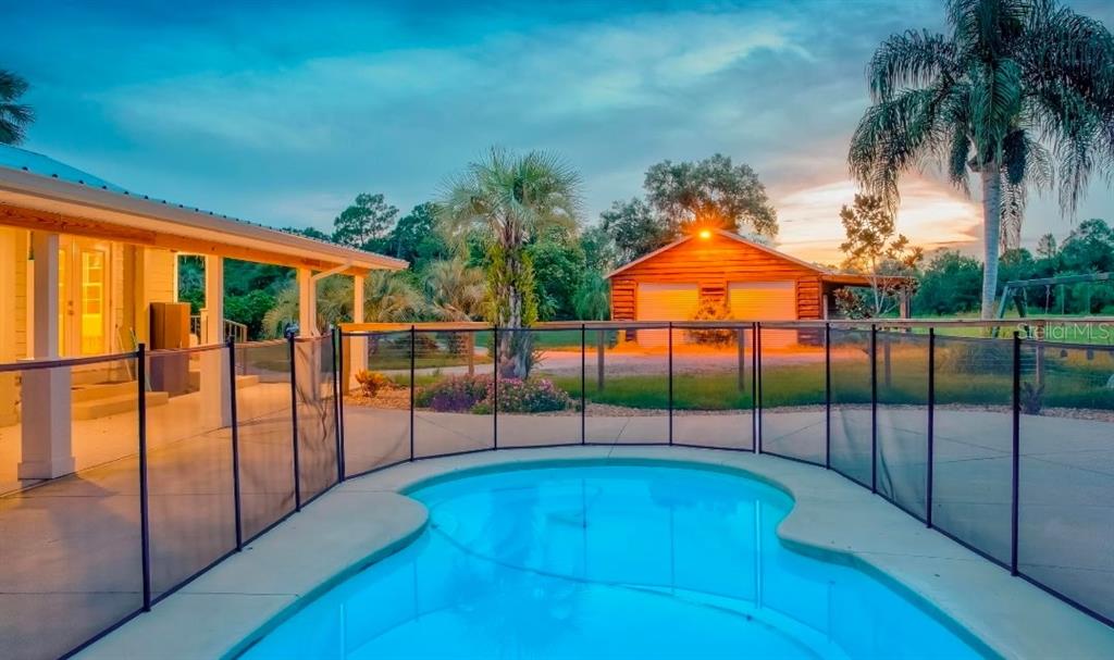 A swimming pool with a black safety fence sits in the backyard of a house — 909 S COUNTY ROAD 3, PIERSON, FL
