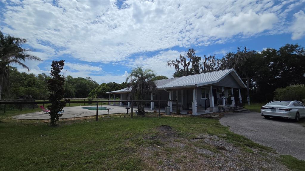 A single-story house with a metal roof, a wrap-around porch, and an outdoor swimming pool — 909 S COUNTY ROAD 3, PIERSON, FL