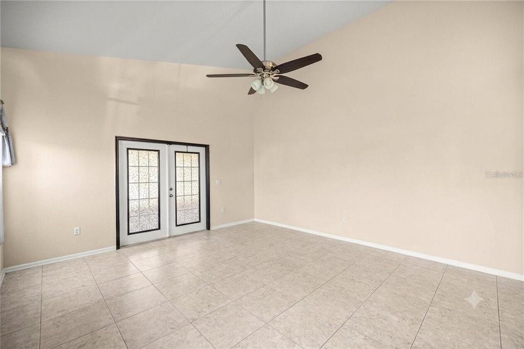 A room with light-colored tile floors, a vaulted ceiling, a ceiling fan, and French doors — 5438 SW 49TH AVENUE, OCALA, FL