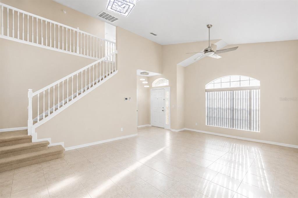 An open living area features a staircase, tile flooring, a ceiling fan, and arched windows — 5438 SW 49TH AVENUE, OCALA, FL