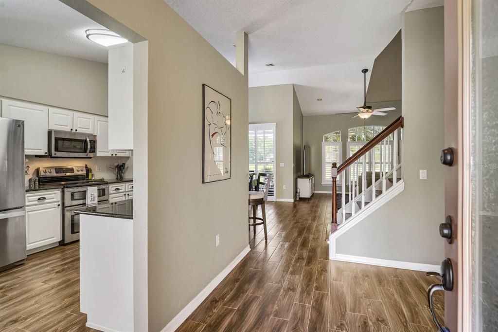 An entryway leads to a kitchen with stainless steel appliances and a staircase with wood railings — 11330 TEE TIME CIRCLE, NEW PORT RICHEY, FL