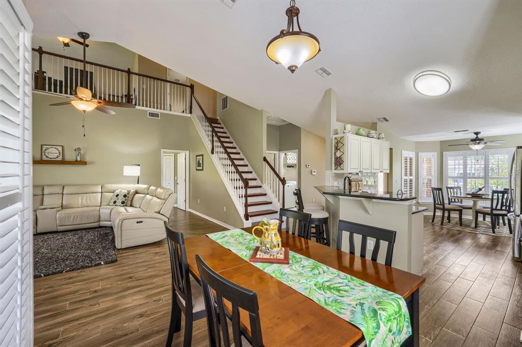 An open-concept living and dining area with wood-look tile floors and a staircase — 11330 TEE TIME CIRCLE, NEW PORT RICHEY, FL