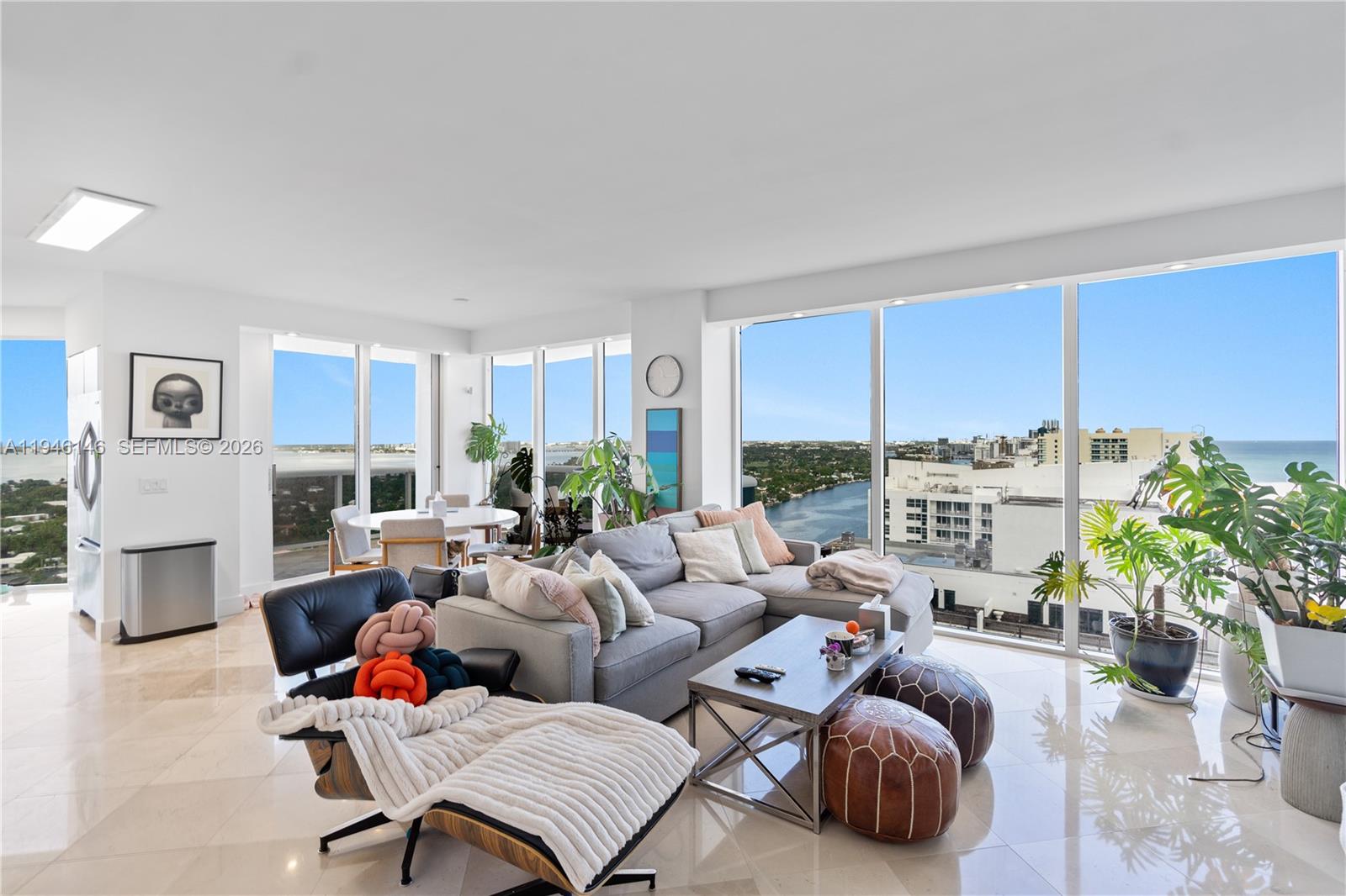 A bright living room features a grey sectional sofa, an Eames-style lounge chair, and floor-to-ceiling windows — 4779 Collins Ave # 2607, Miami Beach FL 33140, MIAMI BEACH, FL