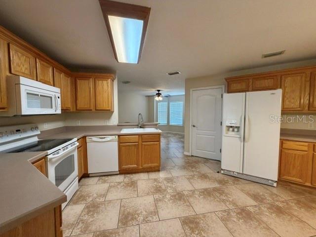 A kitchen with oak cabinets, white appliances, and light-colored tile flooring — 36022 MICHIGAN DRIVE, EUSTIS, FL