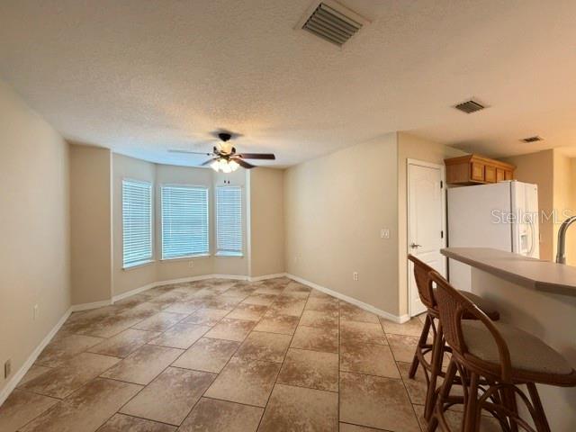 A dining area with tile flooring, a ceiling fan, and a breakfast bar with stools — 36022 MICHIGAN DRIVE, EUSTIS, FL
