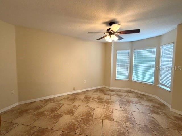 An empty room features beige walls, a ceiling fan, and light-colored tile flooring — 36022 MICHIGAN DRIVE, EUSTIS, FL