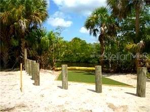 A sandy area features wooden pilings and a small patch of green turf near water — 24183 SAVORY LANE, PUNTA GORDA, FL
