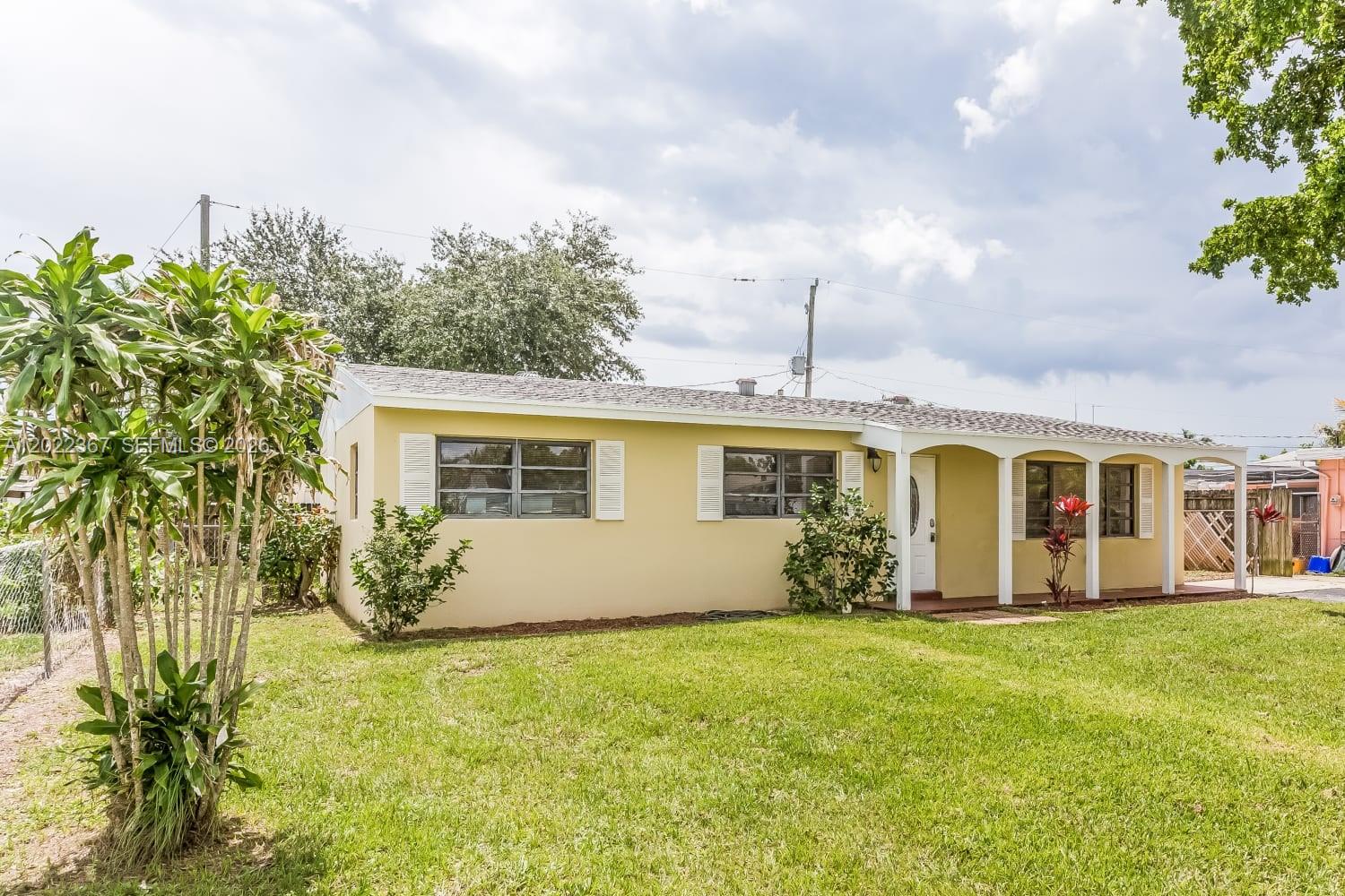A single-story yellow house with a covered porch and a grassy front yard — PALM BEACH GARDENS, FL