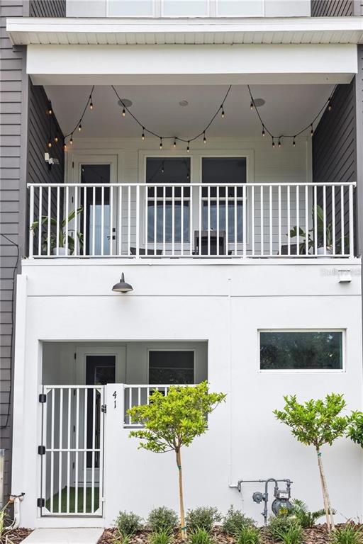 A two-story building exterior features a white stucco ground floor, a balcony, and string lights — 41 29TH STREET N, ST PETERSBURG, FL