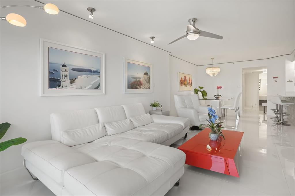 A bright living room features a white sectional sofa, a red coffee table, and artwork — 5207 S ATLANTIC AVENUE UNIT 1023, NEW SMYRNA BEACH, FL