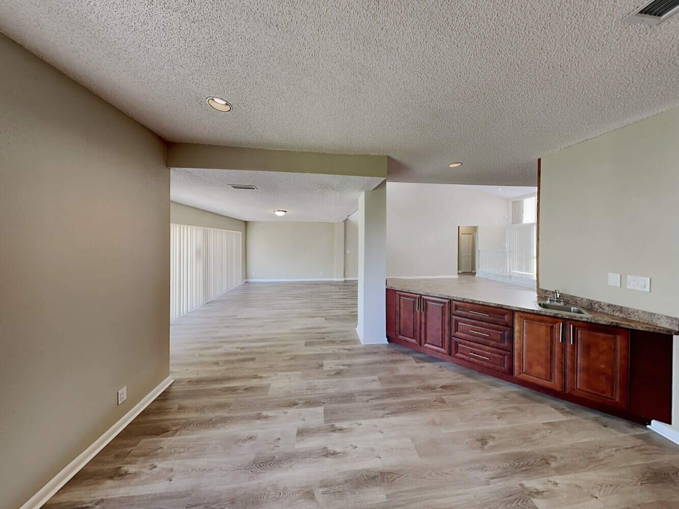 A room with wood-look flooring and a wet bar featuring dark wood cabinets and countertops — TAMARAC, FL