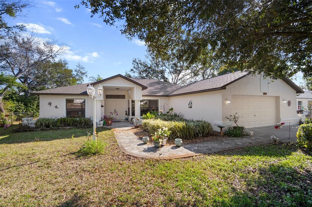 A single-story house with a beige exterior, a stone walkway, and a two-car garage — 1472 IVYDALE ROAD, SPRING HILL, FL